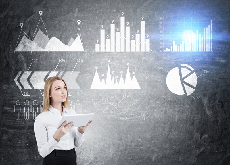 Portrait of blond woman with tablet standing near blackboard with graphs on it. Blue flare. Concept of big data. Mock up