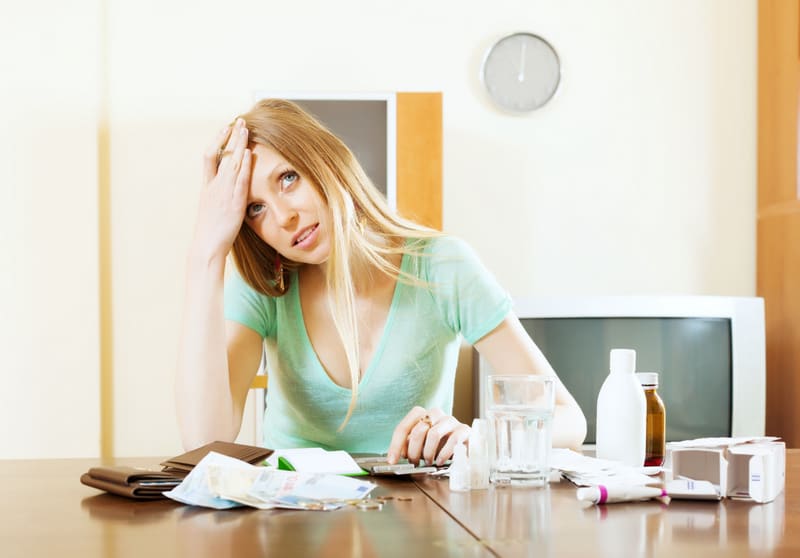 Unhappy pensive woman counting the cost of medications for treatment at home