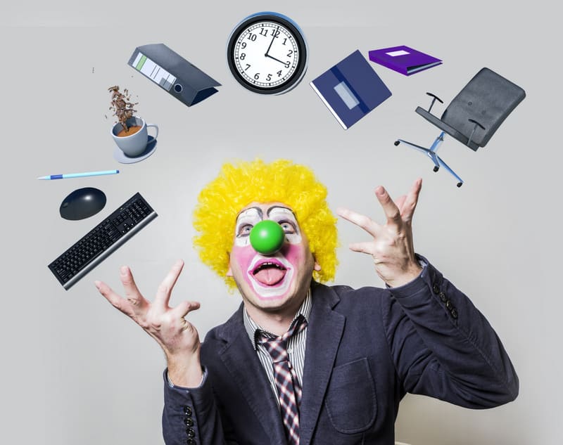 clown raised his hands juggling objects of office life as a symb