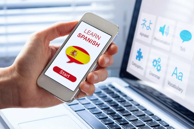 Learn Spanish language online concept with a person showing e-learning app on mobile phone with the flag of Spain