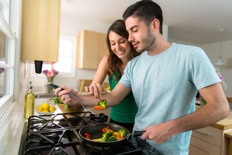 Young attractive couple preparing dinner on a date saving money