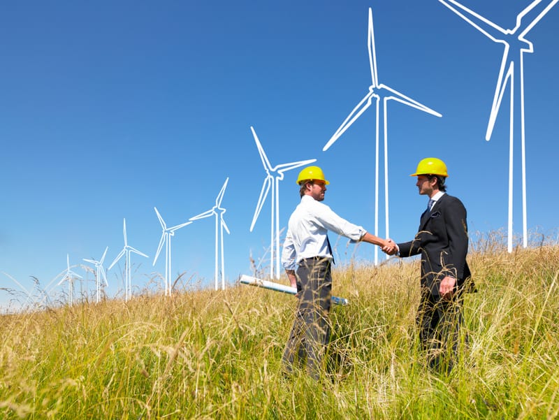 Engineers in field with plans building windmills