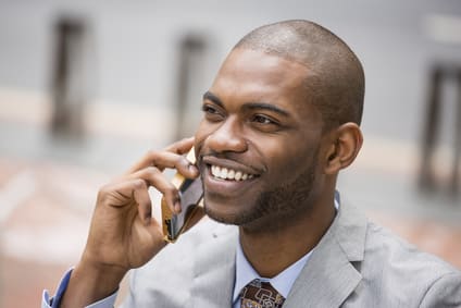 Closeup headshot handsome happy laughing young businessman talking on mobile phone outdoors