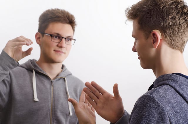 Two teenagers communicating with sign language, selective focus