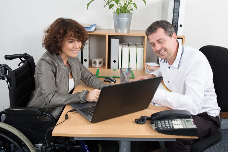 Confident disabled business woman in wheelchair working at office desk