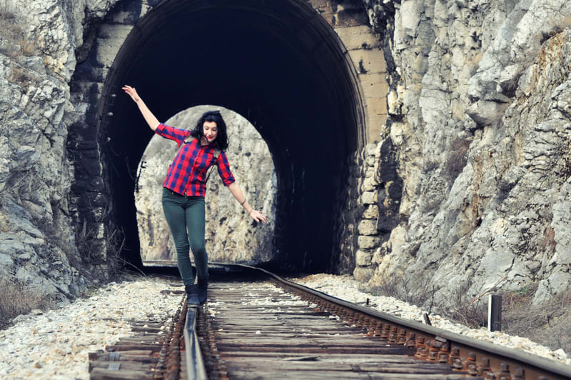 Girl walking on railway line in front of tunnel. Long travel thr