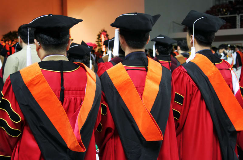 Three Asian university graduates in gowns