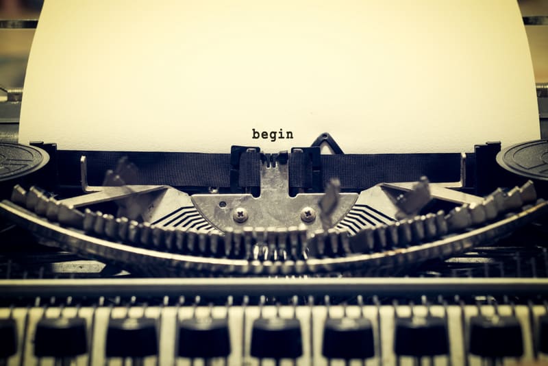 Words "begin" written with old typewriter on white paper in vintage style