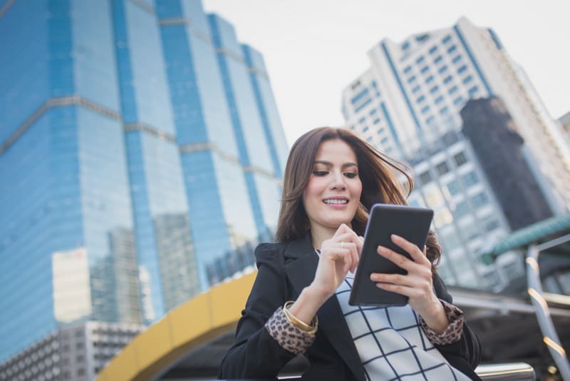 Smart business woman looking confident and smiling holding tablet computer