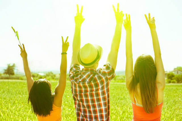 Multiracial friends putting hands up in countryside with back lighting - Multi ethnic young people enjoying sunny day outdoor in nature - Freedom in nature concept - Focus on hat - Vintage filter