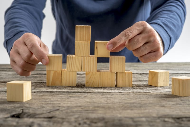 Man Assembling Wooden Cubes on Table