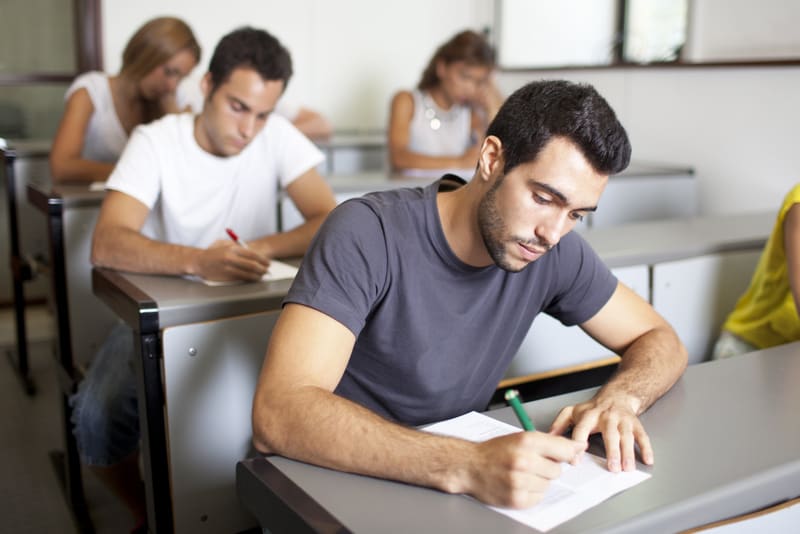 Good-looking male student writing an exam