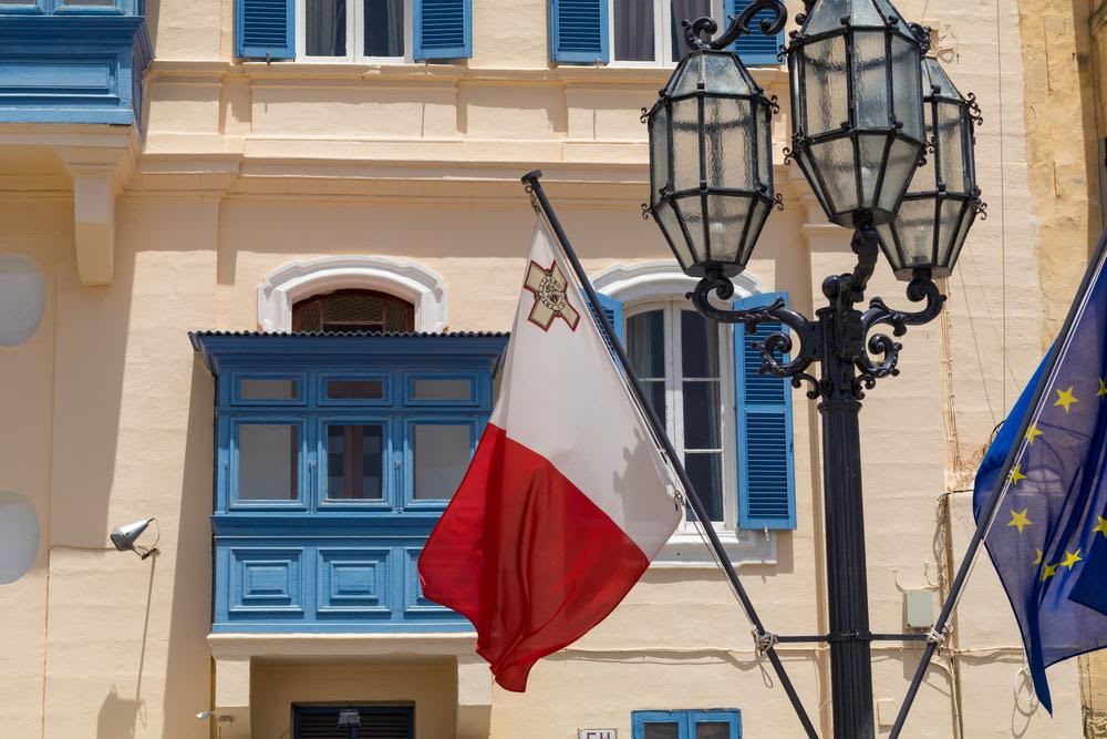 Bandera de Malta y la UE frente a los tradicionales balcones azul malteses, con antiguo lampost, Valletta, Malta