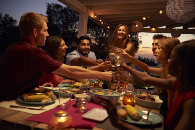Friends make a toast at a dinner party on a patio,