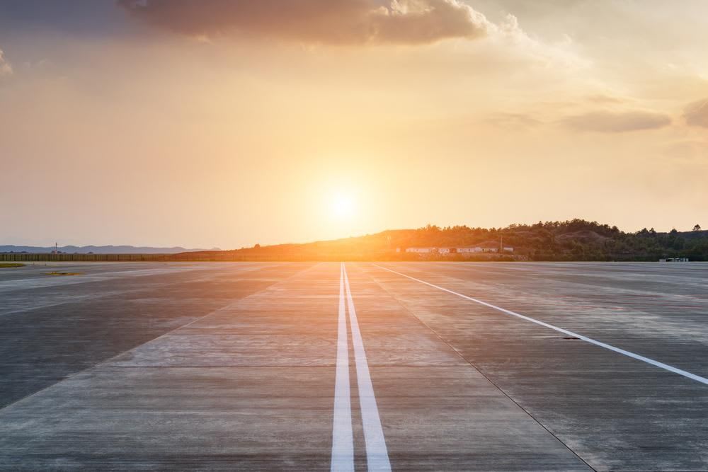 Runway, airstrip in the airport terminal with marking on blue sky with clouds background. Travel aviation concept.