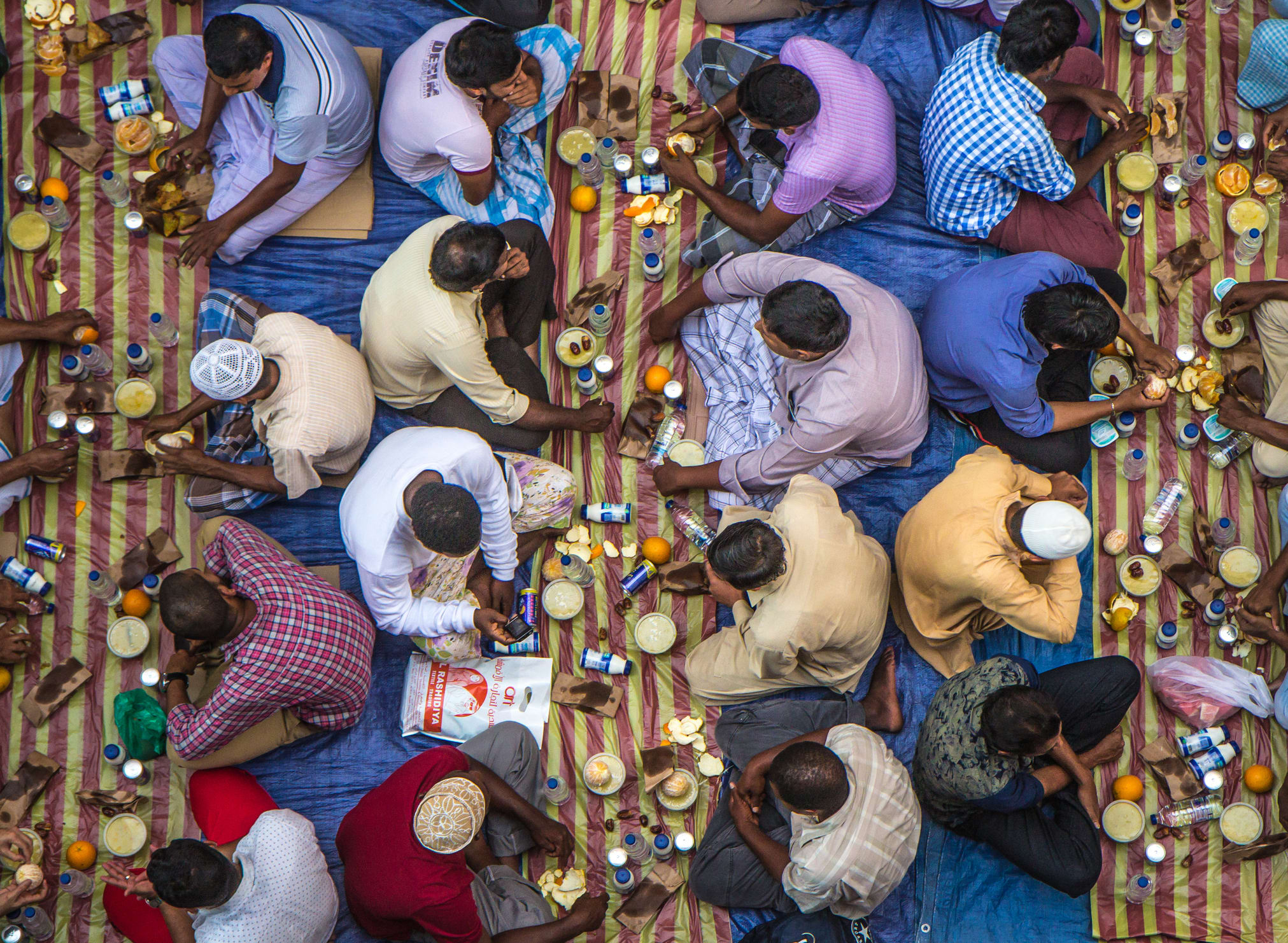 Dubai, UAE - July 16, 2016: Muslim men gathering for a communal charity iftar organised on a street by a local mosque.