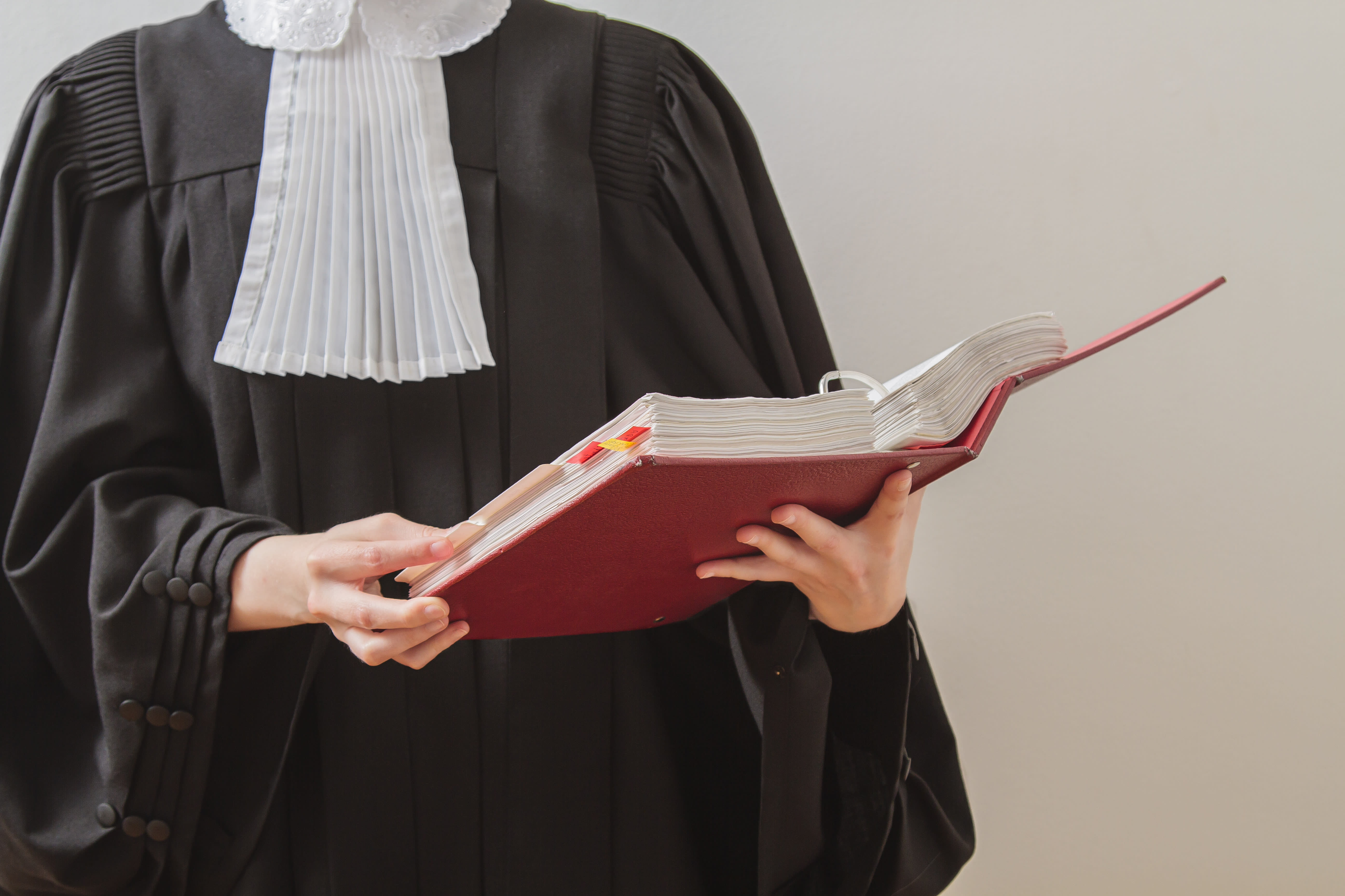 Lawyer in toga, reading from a red law book