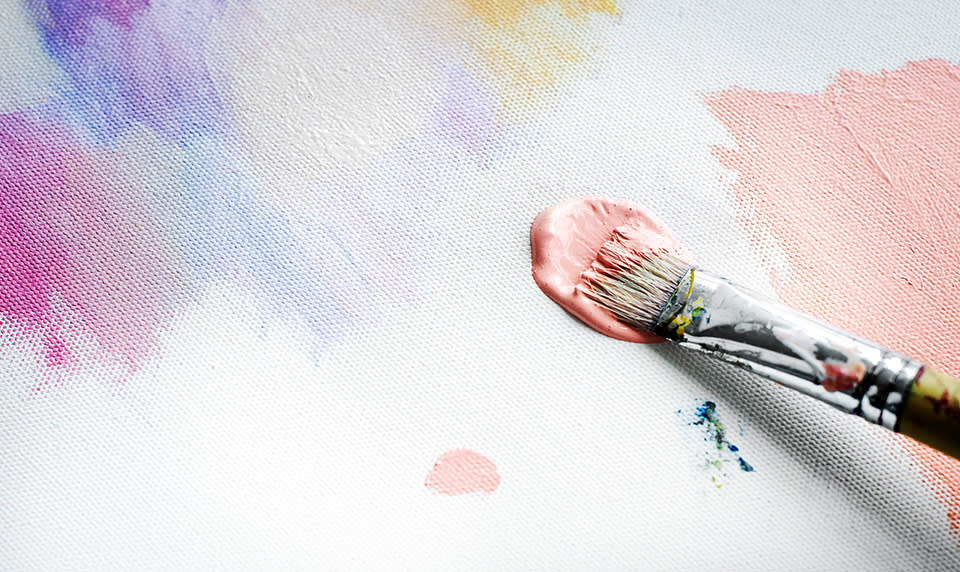 A fine art student paints pastel colors on a canvas