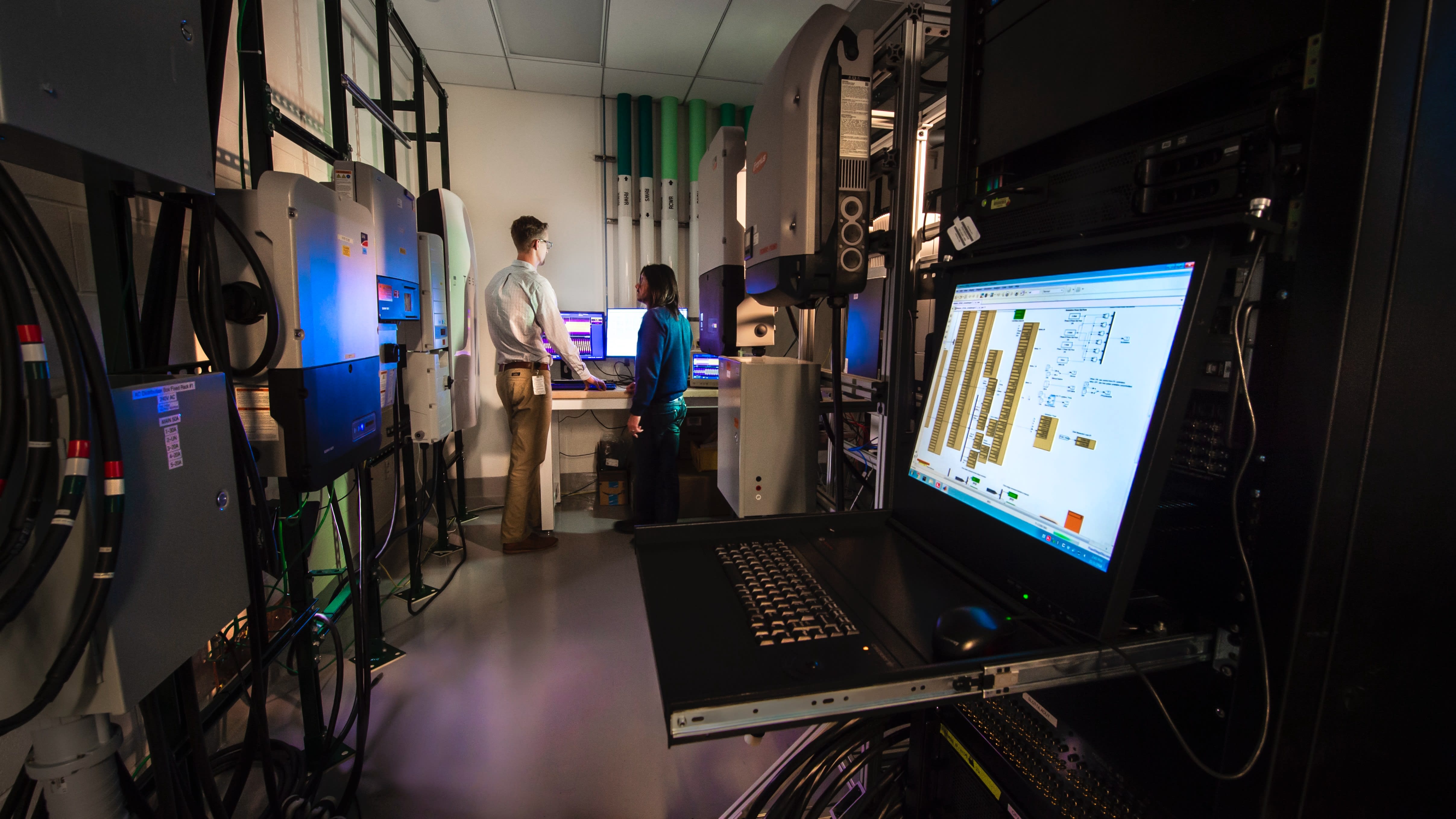 Los investigadores de NREL trabajan en el Laboratorio de rendimiento de sistemas (SPL) en el programa NODES utilizando varios inversores.