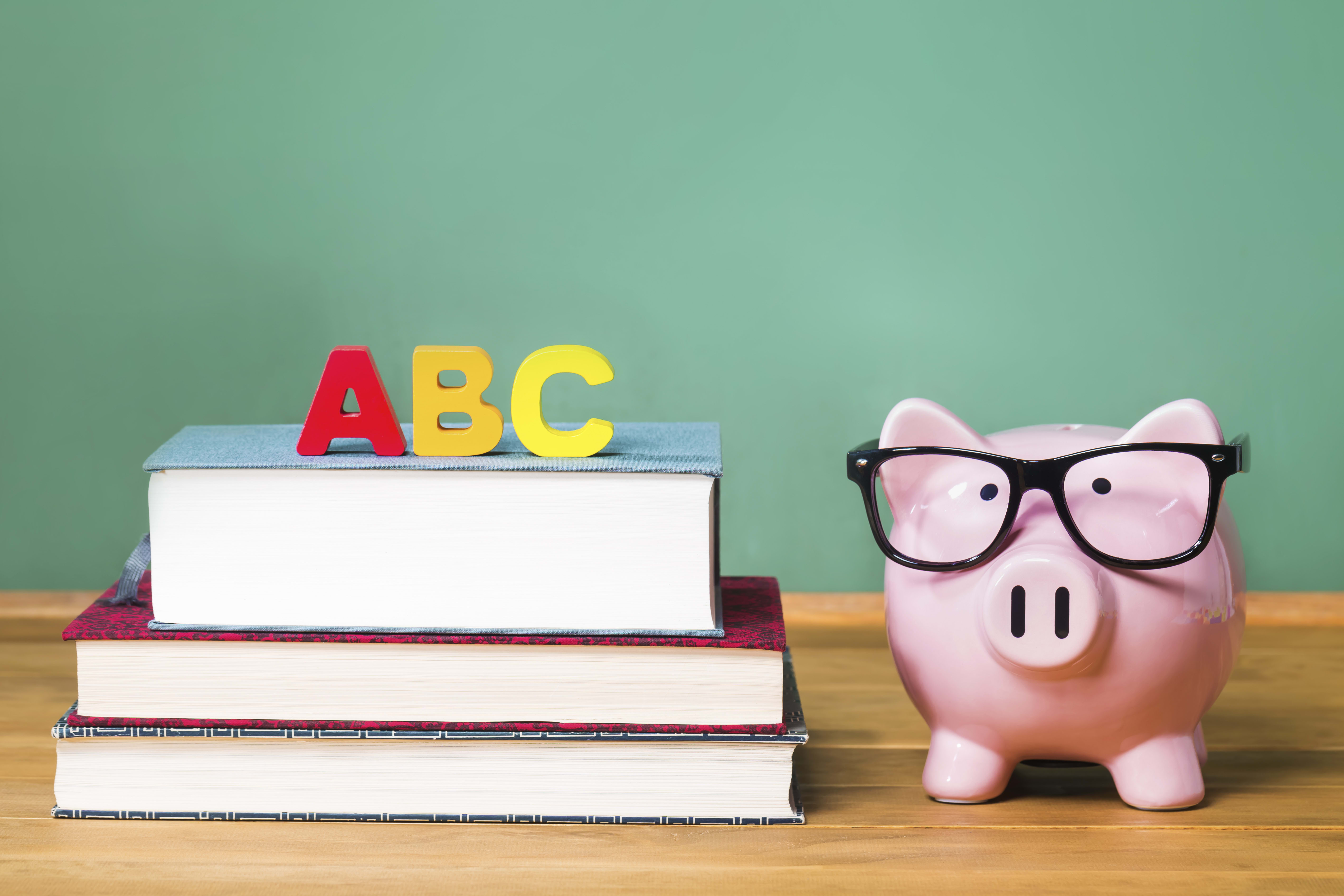School theme with ABCs and pink piggy bank on top of books with chalkboard in the background