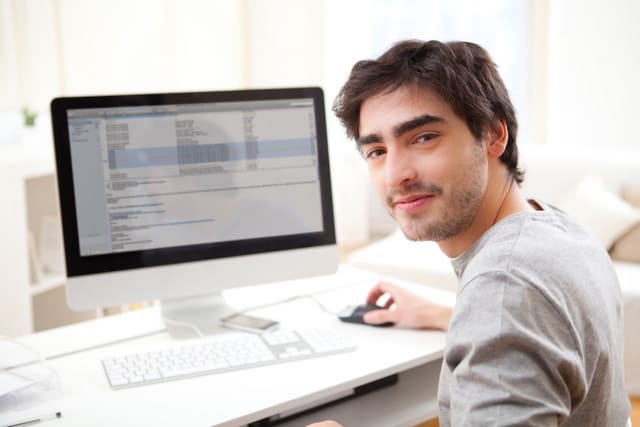 Young smiling man in front of computer