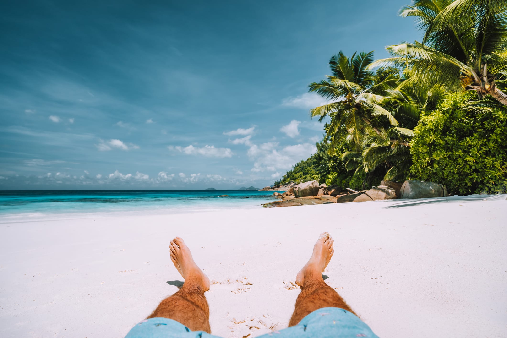 man resting on the white sand beach with beautiful palm trees