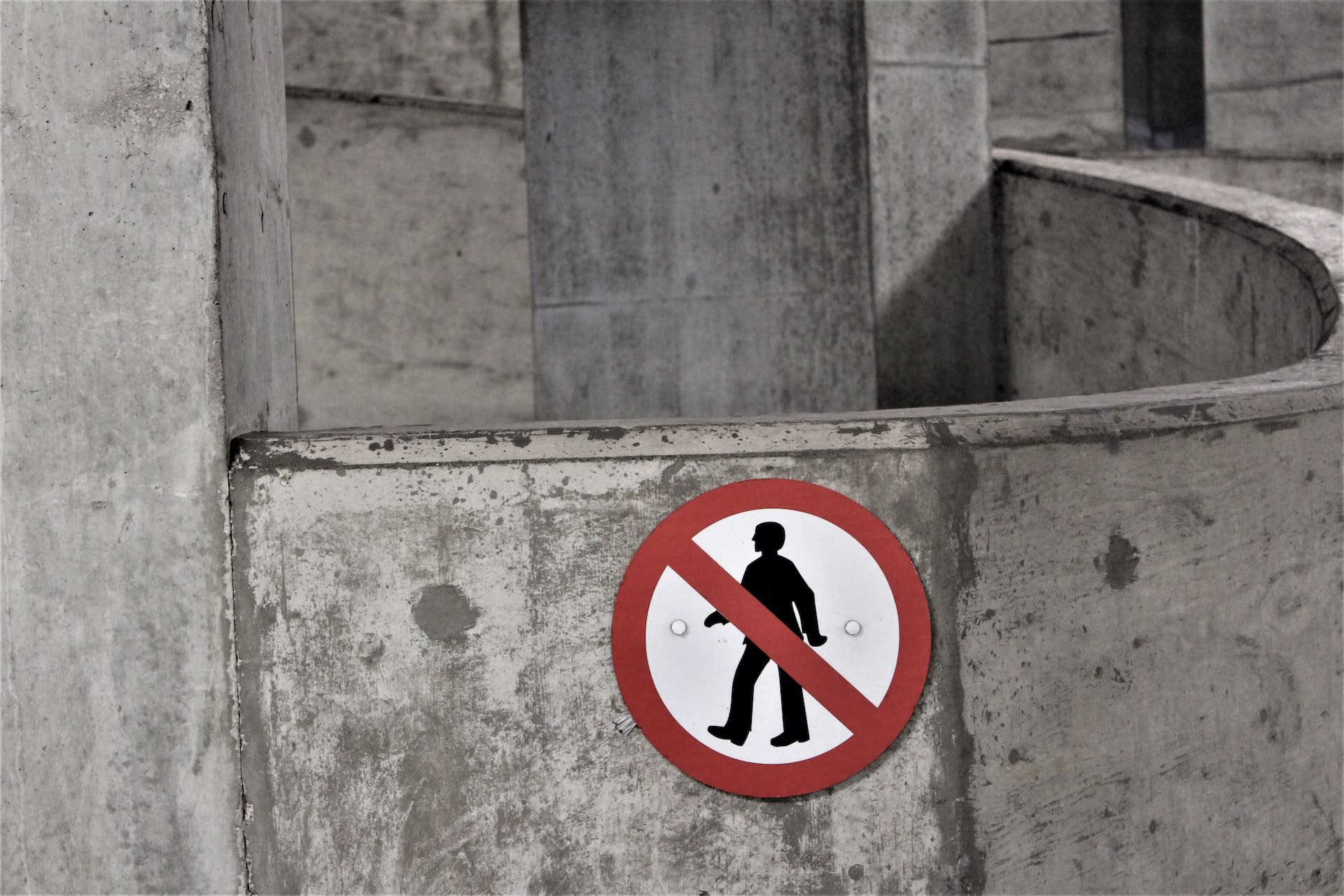 Red warning sign on a cement wall indicating people are not allowed in this area