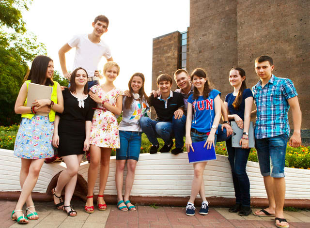 Group of students or teenagers with notebooks outdoors in summer evening