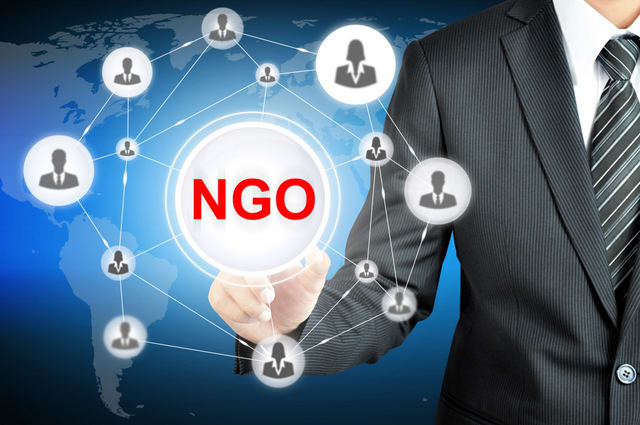 Businessman pointing on NGO (Non-Governmental Organization) sign on virtual screen with people icons linked as network