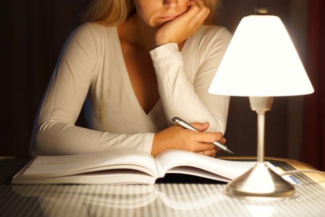 female student is reading book late at night