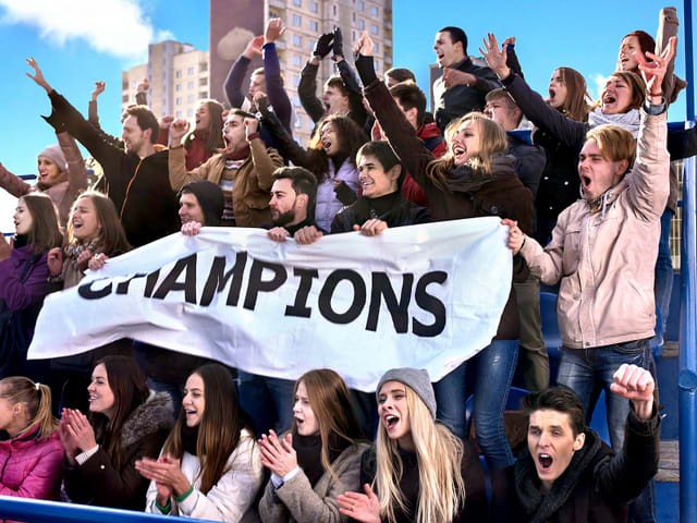 Sport fans holding champion banner on tribunes.