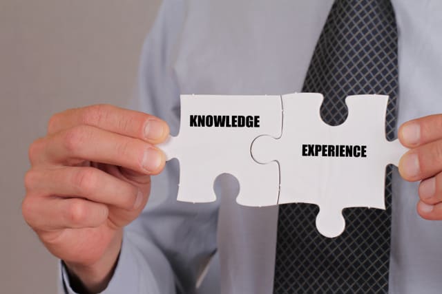 Business success concept. Connection between Knowledge and Experience, Businessman holding two pieces of a puzzle close up