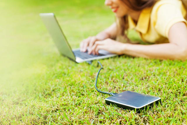 woman using hard drive disk to backup her data while lying down