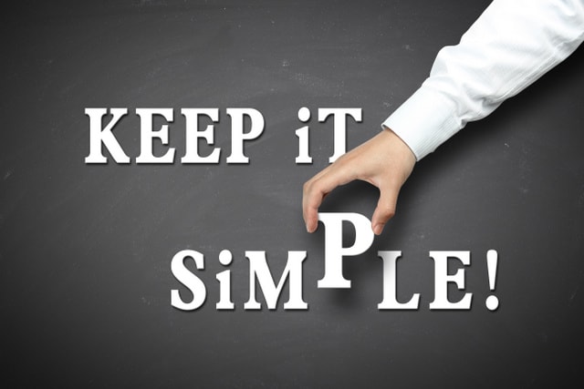 Keep it simple concept with businessman hand holding against blackboard background.