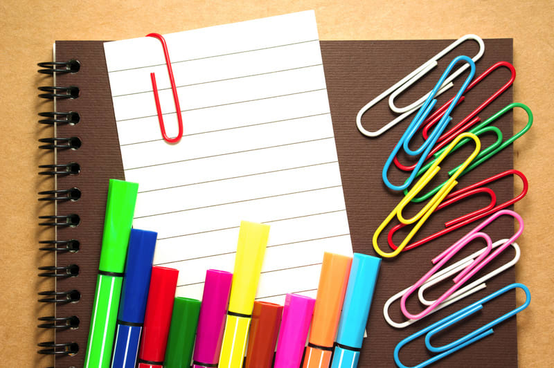 Note paper clip on notebook with colorful marker pen and paperclips on brown cardboard background