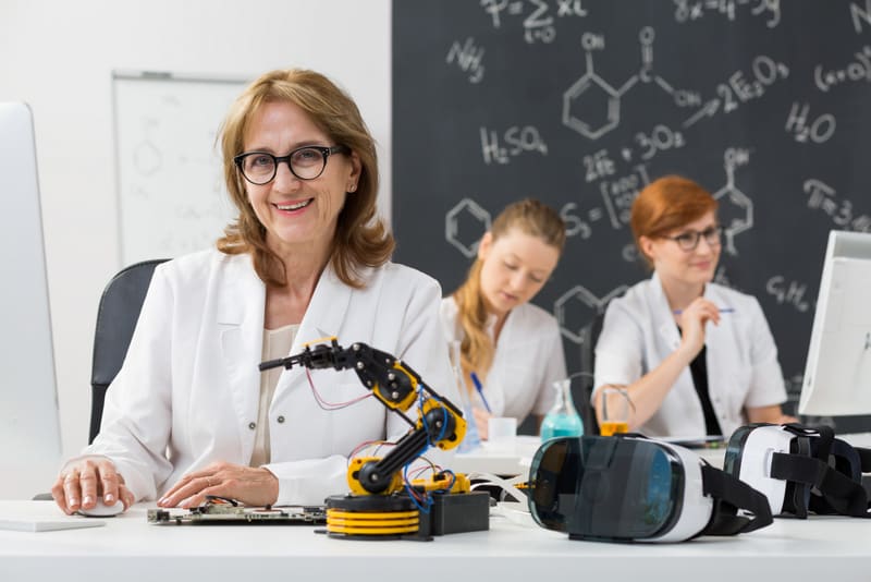 Shot of a smiling professor sitting in a classroom with her students