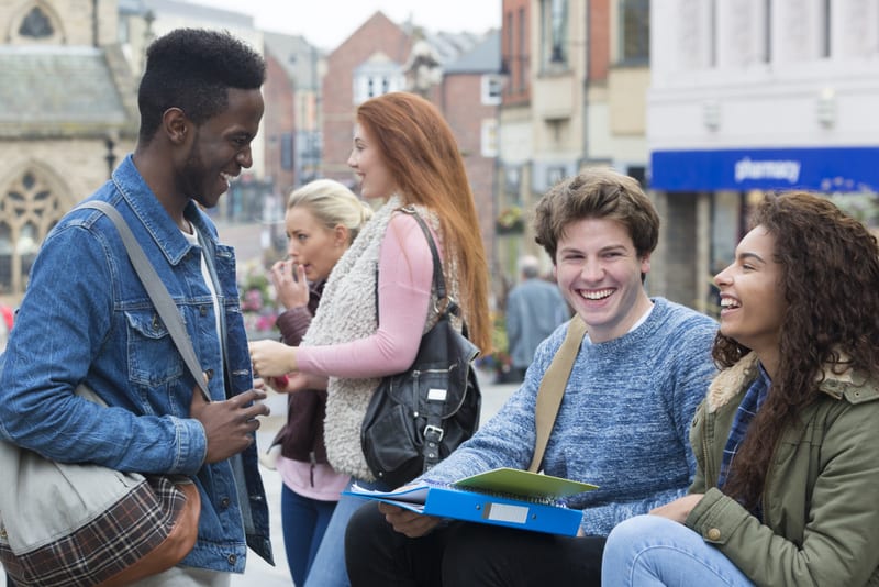 Group of students sitting outdoors studying while on a break from university. They are sitting in the city centre.