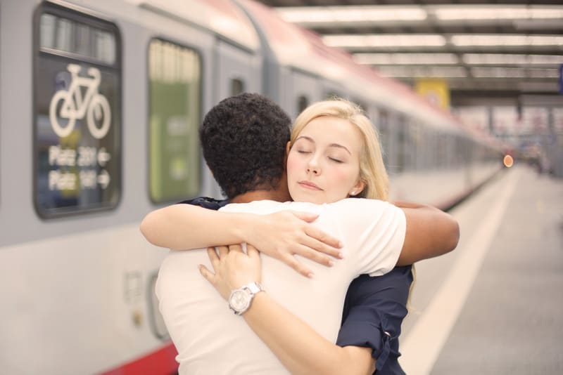Interracial couple hugging at the train station