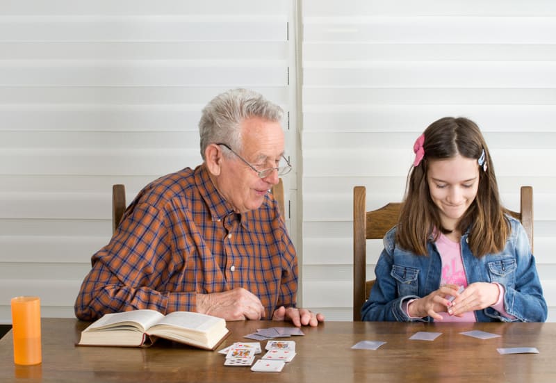 Grandpa and granddaughter playing memory game with cards