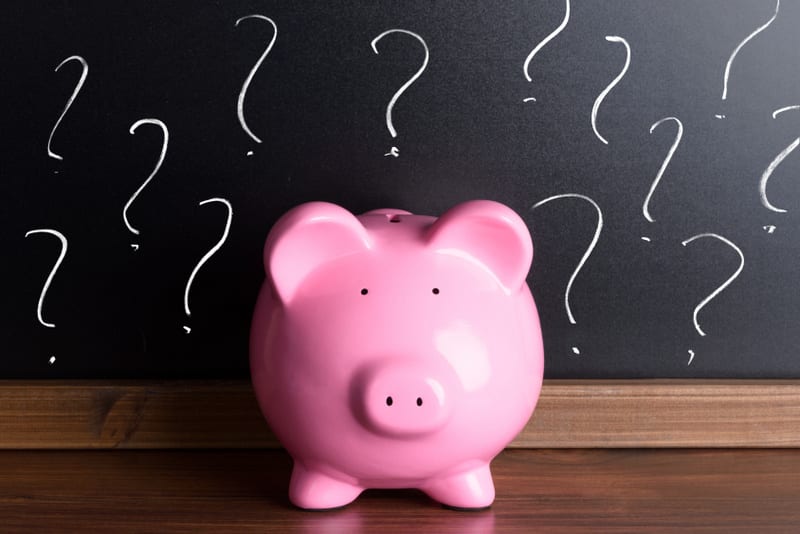 Piggy Bank In Front Of A Blackboard With Question Marks