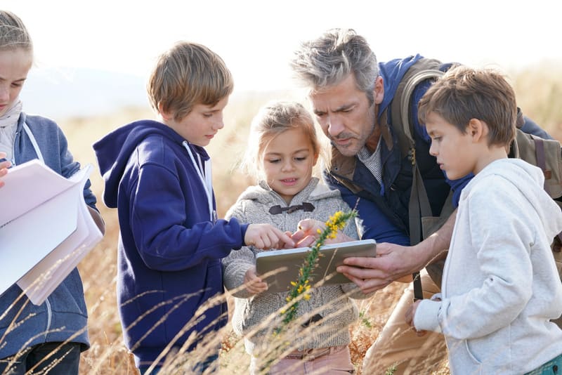Teacher taking kids to countryside to explore plants and flowers