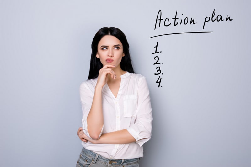 Portrait of cute young  woman with pouted sensual lips and black hair fink about new idea and looking at drawn list of action plan. Copy space on item