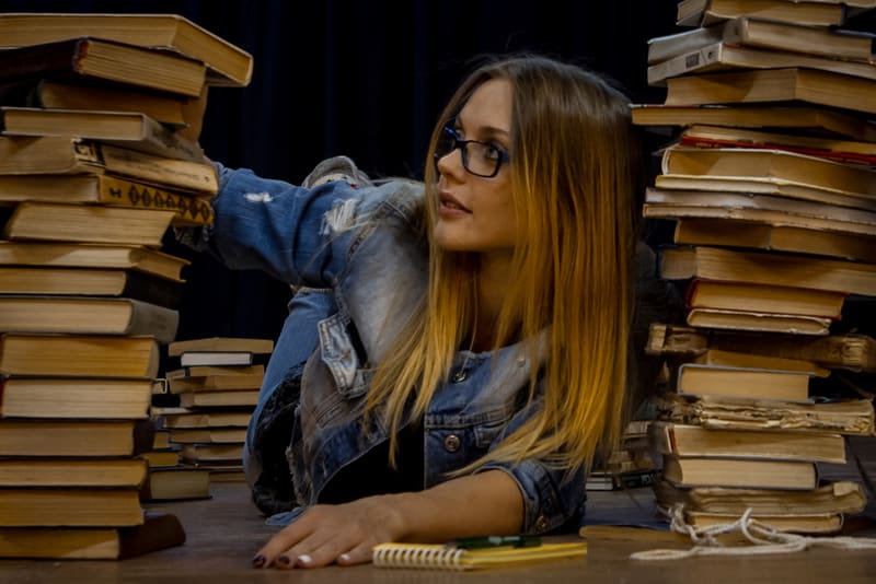 Girl student with books piled up with studying science