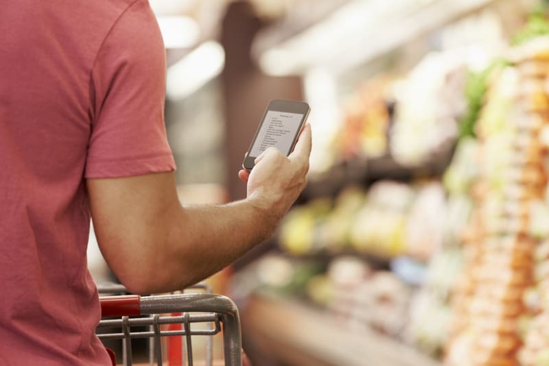 Man with shopping cart reads from cell phone