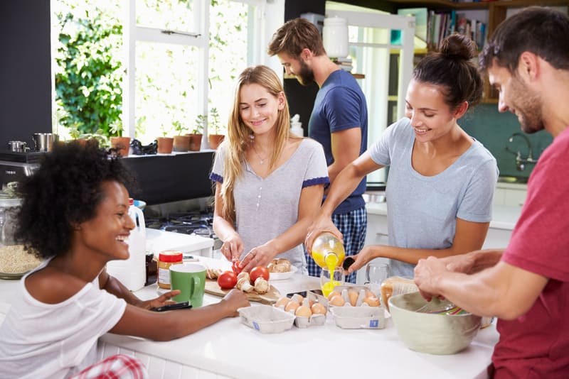 Group Of Friends Cooking Breakfast In Kitchen Together