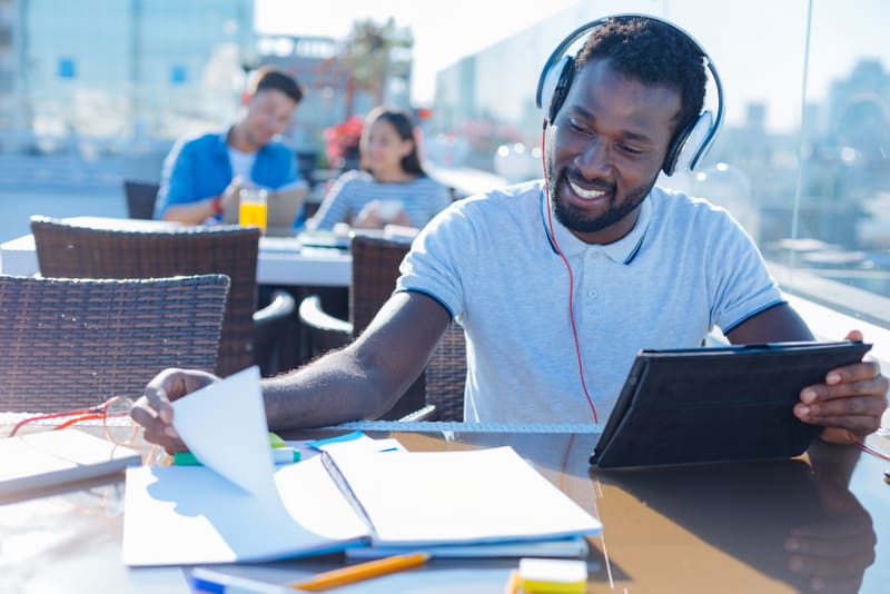 African american student with headphones studying outdoors