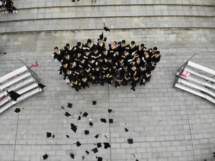 group of graduates throwing academic hats group of graduates throwing academic hats