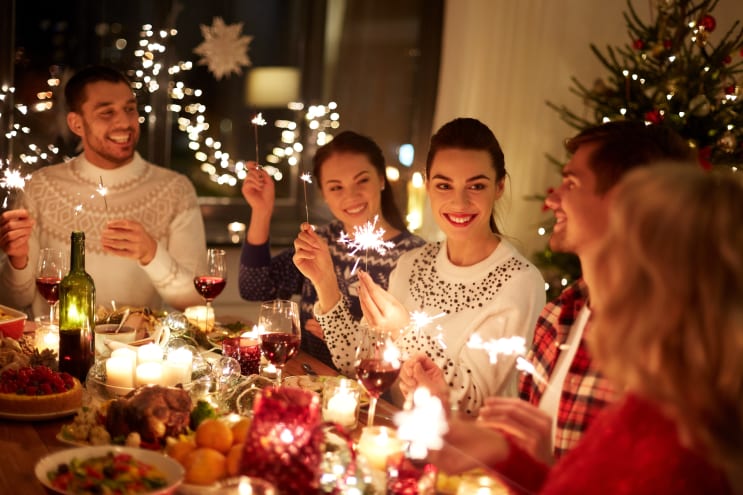 winter holidays and people concept - happy friends with sparklers celebrating christmas at home feast