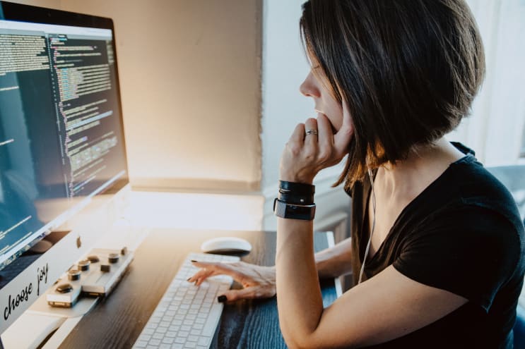 Woman sitting at a desk in front of coding computer screen Woman sitting at a desk in front of coding computer screen