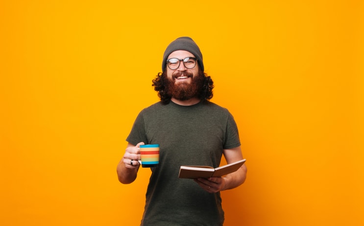 Happy man with coffee and book looking confident at the camera stock photo